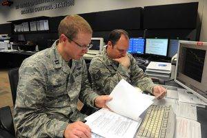 Capt. Adam Moody, 2SOPS GPS Operations Support flight commander, and Staff Sgt. Carl Ellinger, 2 SOPS GPS mission chief, review a checklist of procedures for a transfer operation at Schriever Air Force Base. (U.S. Air Force photo/Dennis Rogers)